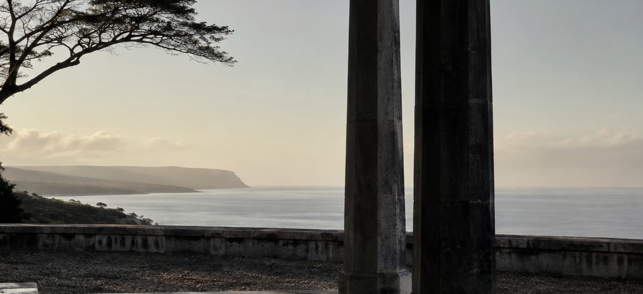 Editorial study of a quiet sea horizon framed by weathered columns.