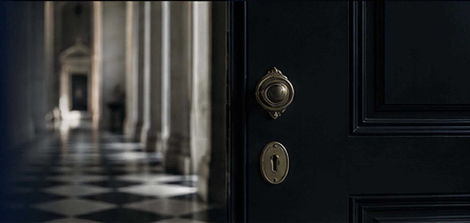 Editorial study of a dark doorway opening towards a colonnaded interior.